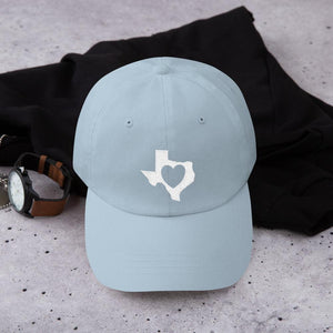 heart in Texas on light blue hat on the counter with a watch